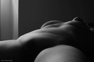 Corps d'une femme allongée sur le dos avec une lumière tamisée pour accentuer les courbes